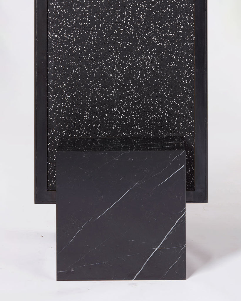 Cube base detail image of standing mirror with nero marquina marble base and blackened steel mirror frame, speckled black rubber back.